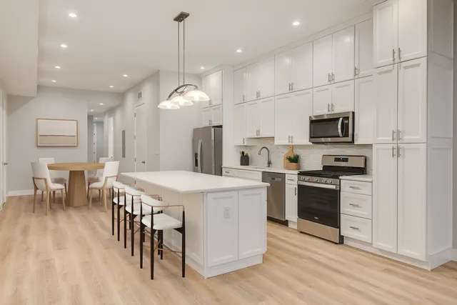 a kitchen with kitchen island granite countertop a stove oven a sink dishwasher and a refrigerator with wooden floor