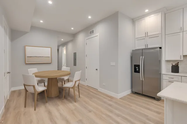 a kitchen with stainless steel appliances a dining table chairs refrigerator and sink