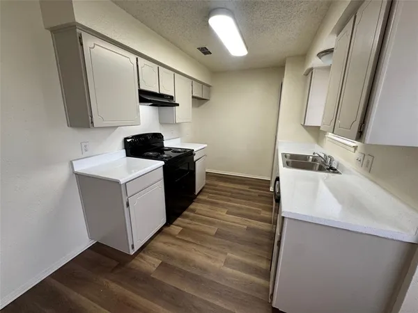 a kitchen with a sink cabinets and wooden floor
