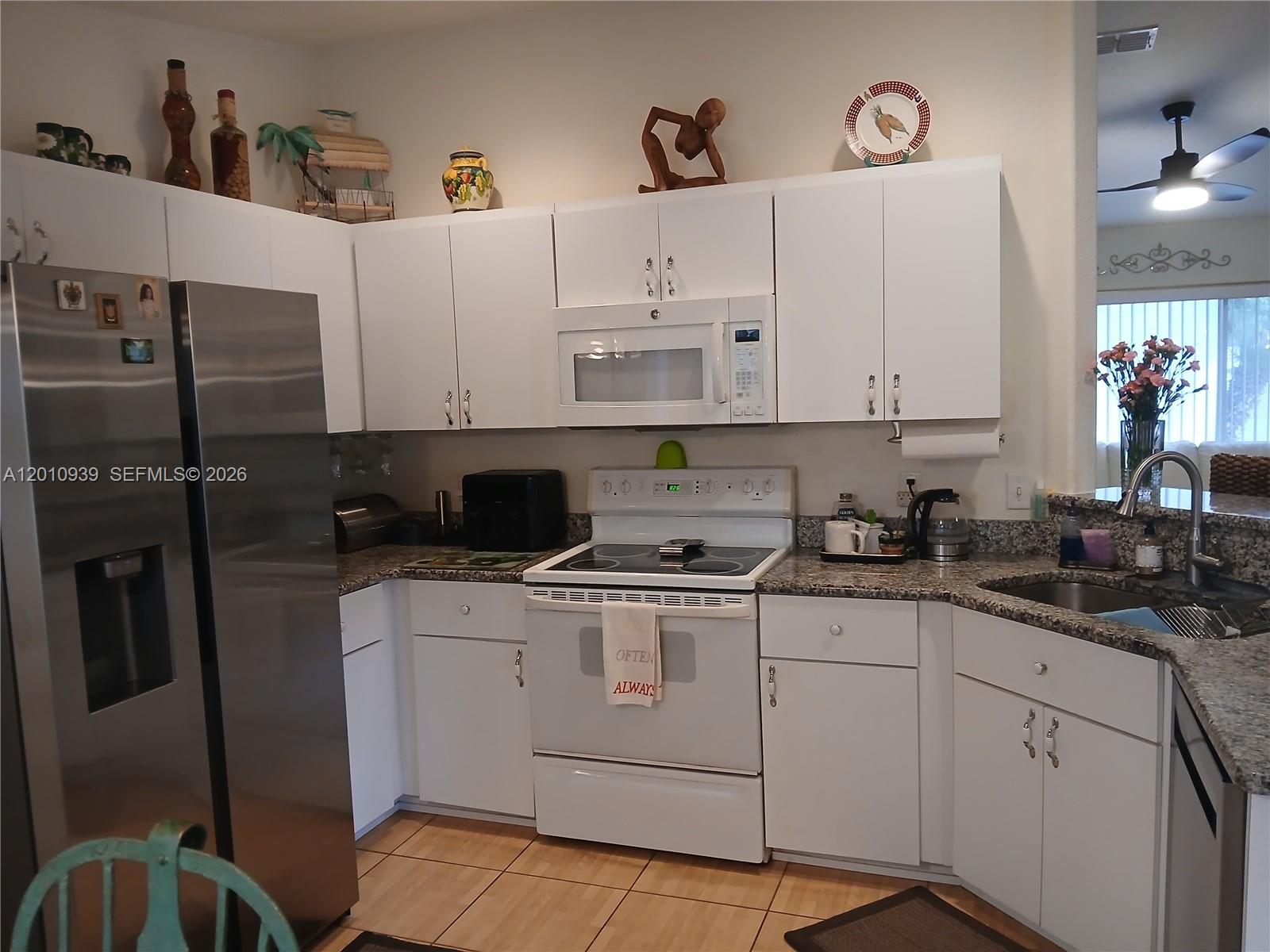 5880 Southwest 102nd Street Ocala, FL 34476 - Photo 8 of 17 a kitchen with stainless steel appliances granite countertop a sink a stove a refrigerator and white cabinets