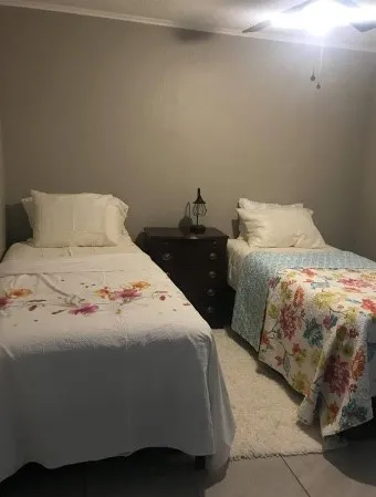 a bedroom with two beds and next to a window