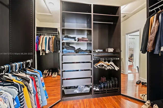 a view of walk in closet with clothes and shoes