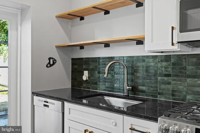 a kitchen with granite countertop a stove a sink and a refrigerator