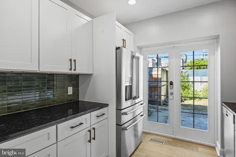 a kitchen with granite countertop a stove a sink and a refrigerator