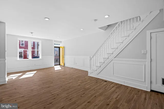 a view of an empty room with wooden floor and stairs
