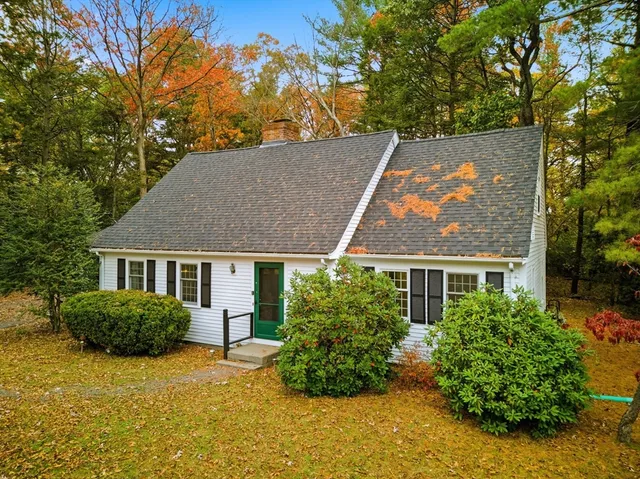 an aerial view of a house with yard and trees in the background