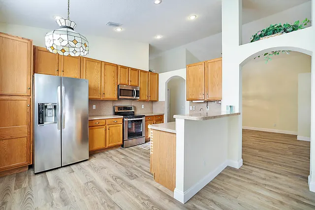 a kitchen with a refrigerator a stove cabinets and wooden floor