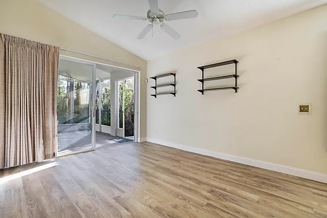 an empty room with wooden floor fan and windows