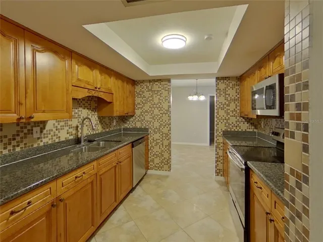 a large kitchen with stainless steel appliances granite countertop a sink and cabinets