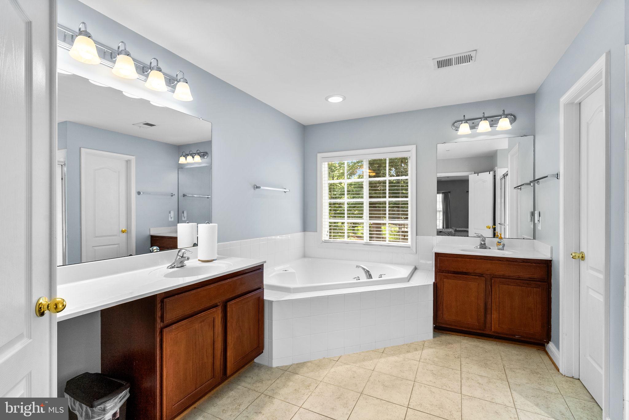 8301 Cedar View Court Clinton, MD 20735 - Photo 18 of 32 a large bathroom with a double vanity sink large mirror and bathtub