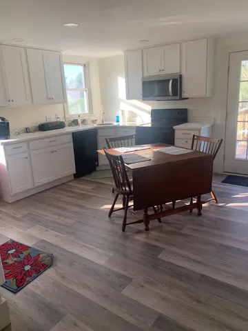 a living room with furniture wooden floor and kitchen view