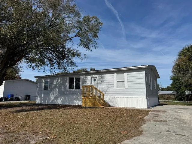 a front view of house with yard and trees in the background