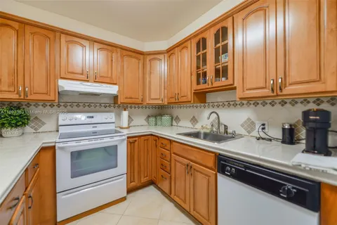 a kitchen with granite countertop stainless steel appliances a stove sink and cabinets