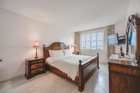 a bedroom with a bed and a flat tv screen on a dresser