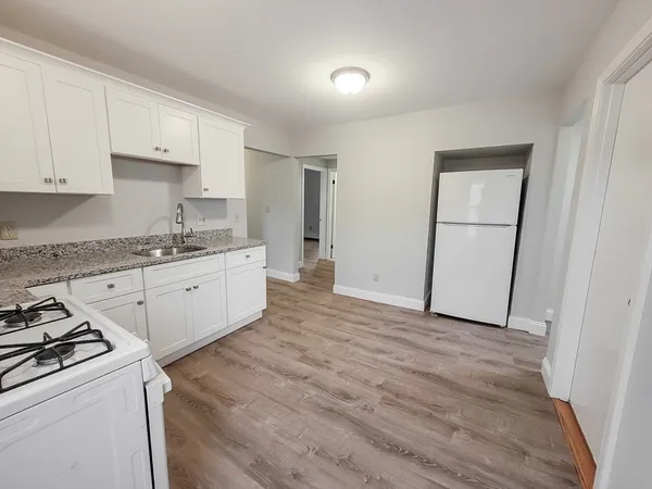 a kitchen with granite countertop white cabinets and white appliances