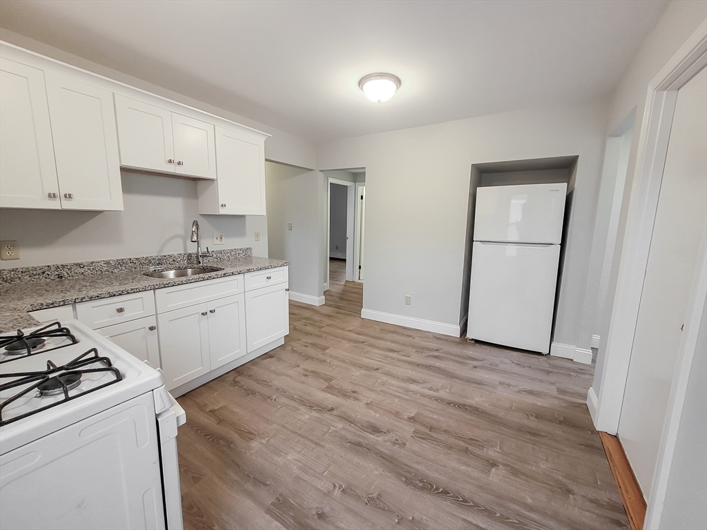 a kitchen with granite countertop white cabinets and white appliances