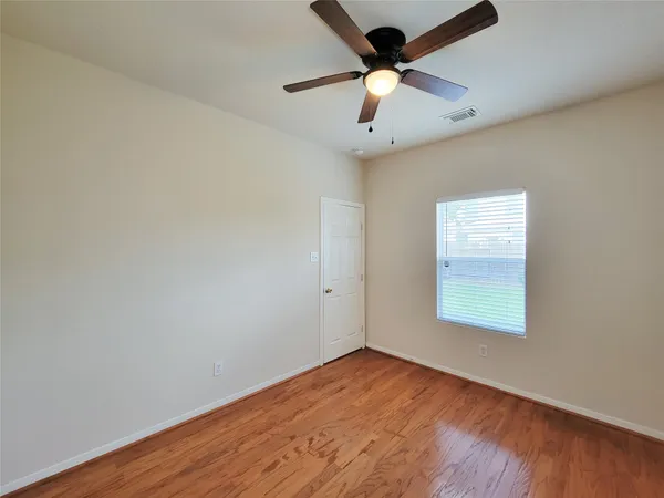 an empty room with a window and a ceiling fan
