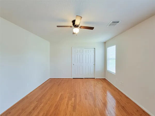 a view of empty room with wooden floor and fan
