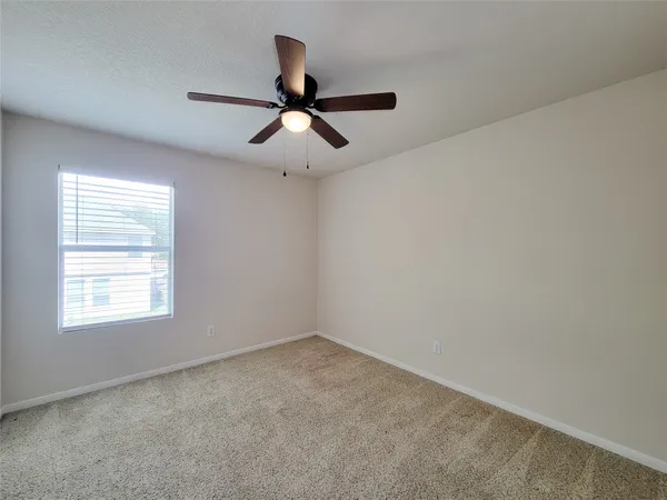 an empty room with a window and a fan