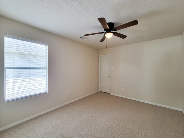 a view of an empty room with a ceiling fan and window
