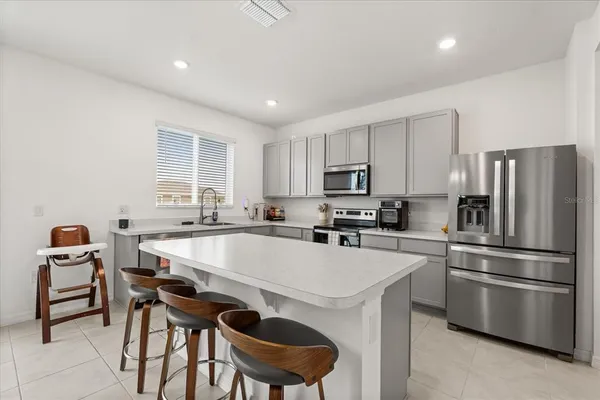 a kitchen with a dining table chairs and refrigerator