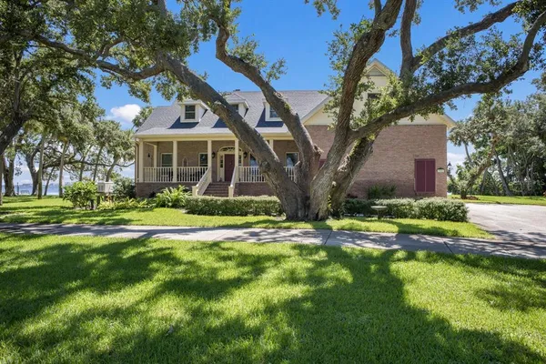 a view of a house with a big yard and large trees