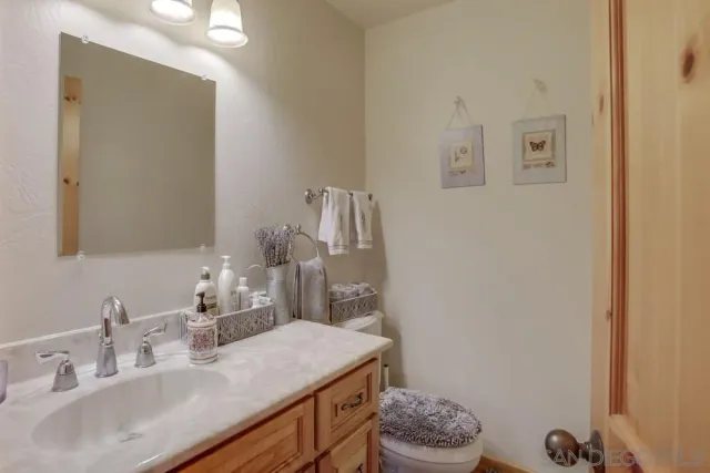 a bathroom with a granite countertop sink a toilet and a mirror