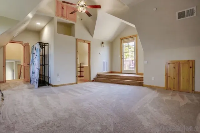 an empty room with windows and ceiling fan