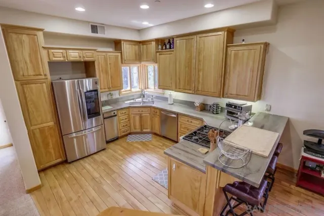 a kitchen with stainless steel appliances granite countertop a refrigerator a stove a sink dishwasher and microwave with wooden floor