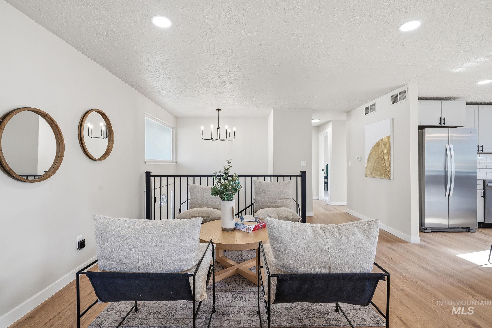 1990 Panama Street Boise, ID 83705 - Photo 14 of 50 Open-concept living area with wood-finish flooring, recessed lighting, a modern black chandelier, and a stainless steel refrigerator