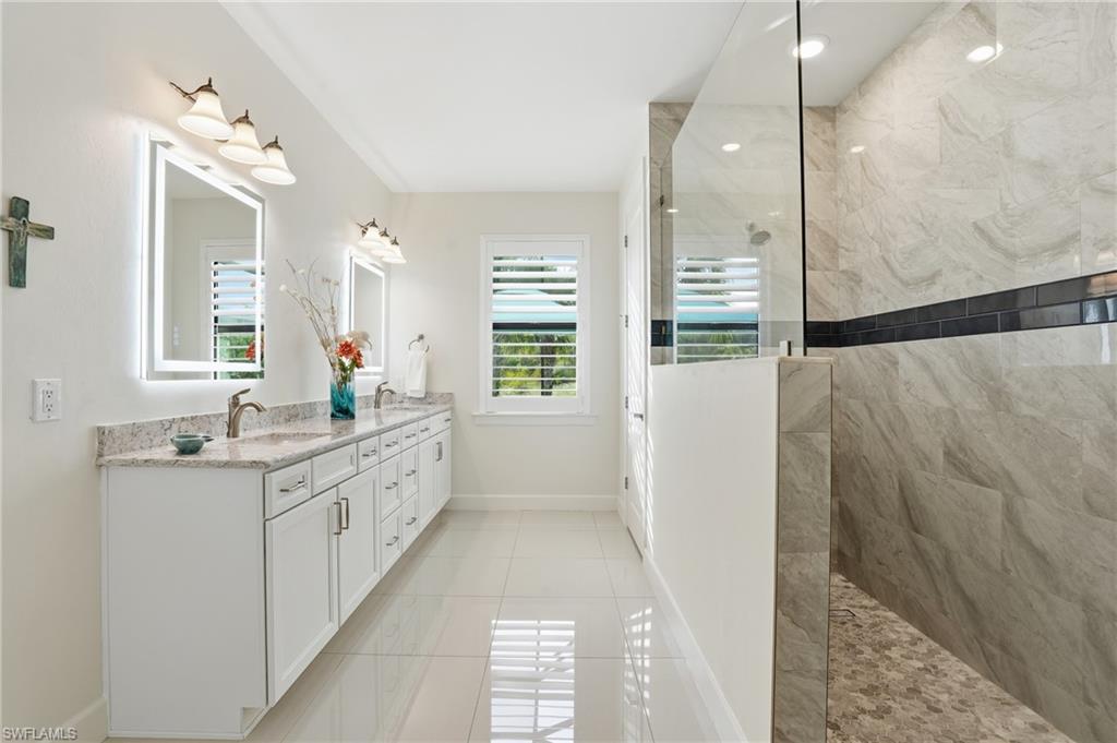 17210 Ashcomb Way Estero, FL 33928 - Photo 20 of 47 a large bathroom with a granite countertop sink a large mirror a shower and vanity