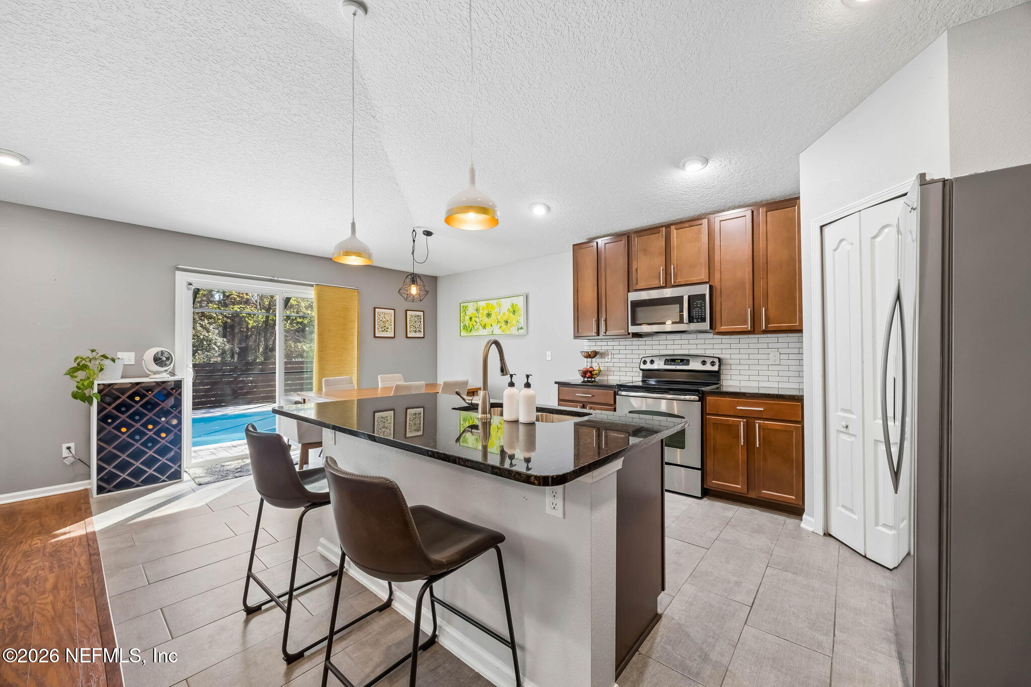 1624 Indigo Street Fernandina Beach, FL 32034 - Photo 11 of 22 a kitchen with stainless steel appliances granite countertop a refrigerator a stove a sink a dining table and chairs with wooden floor