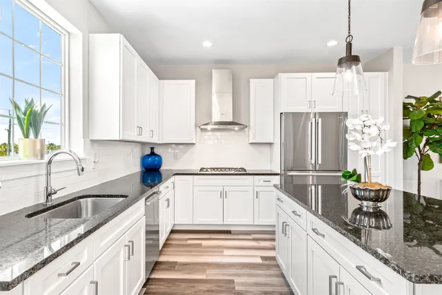 a kitchen with stainless steel appliances granite countertop a sink a stove a refrigerator and island with wooden floor