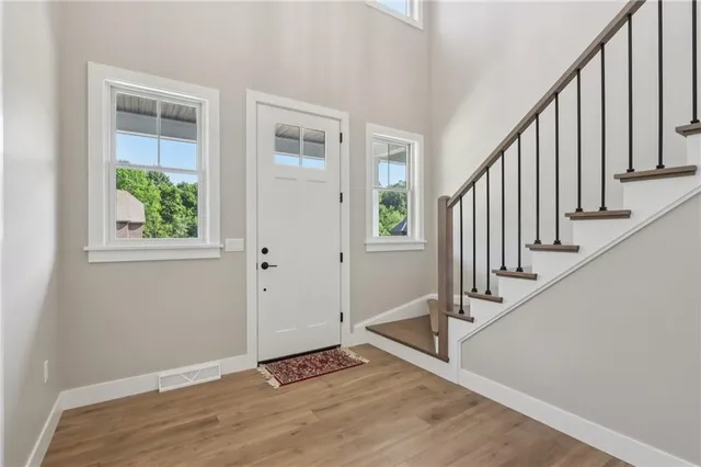 a view of an entryway with wooden floor leading to a furnished livingroom and windows
