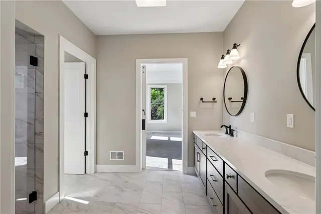 a spacious bathroom with a double vanity sink a mirror and a shower