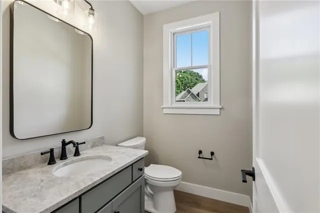 a bathroom with a granite countertop toilet sink and mirror