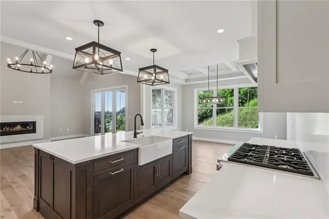 a large white kitchen with a large center island a stove a living room and windows