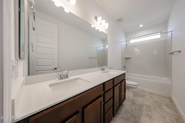 a bathroom with a sink double vanity granite tub and a mirror