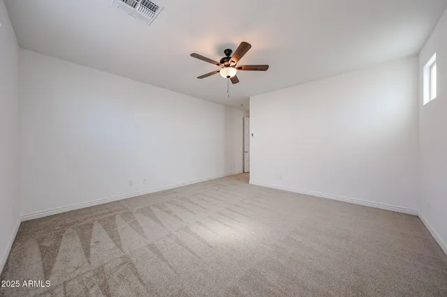an empty room with a window and a ceiling fan