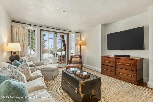 a bedroom with bed a flat tv screen and a dresser