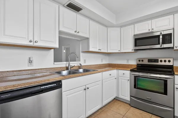 a kitchen with stainless steel appliances granite countertop a sink dishwasher a stove and a microwave oven with white cabinets
