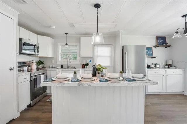 a kitchen with kitchen island granite countertop a sink cabinets and stainless steel appliances
