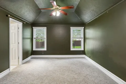 an empty room with windows and fan