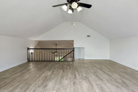 a view of a room with wooden floor fan and windows