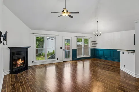 a view of an empty room with wooden floor fireplace and a window