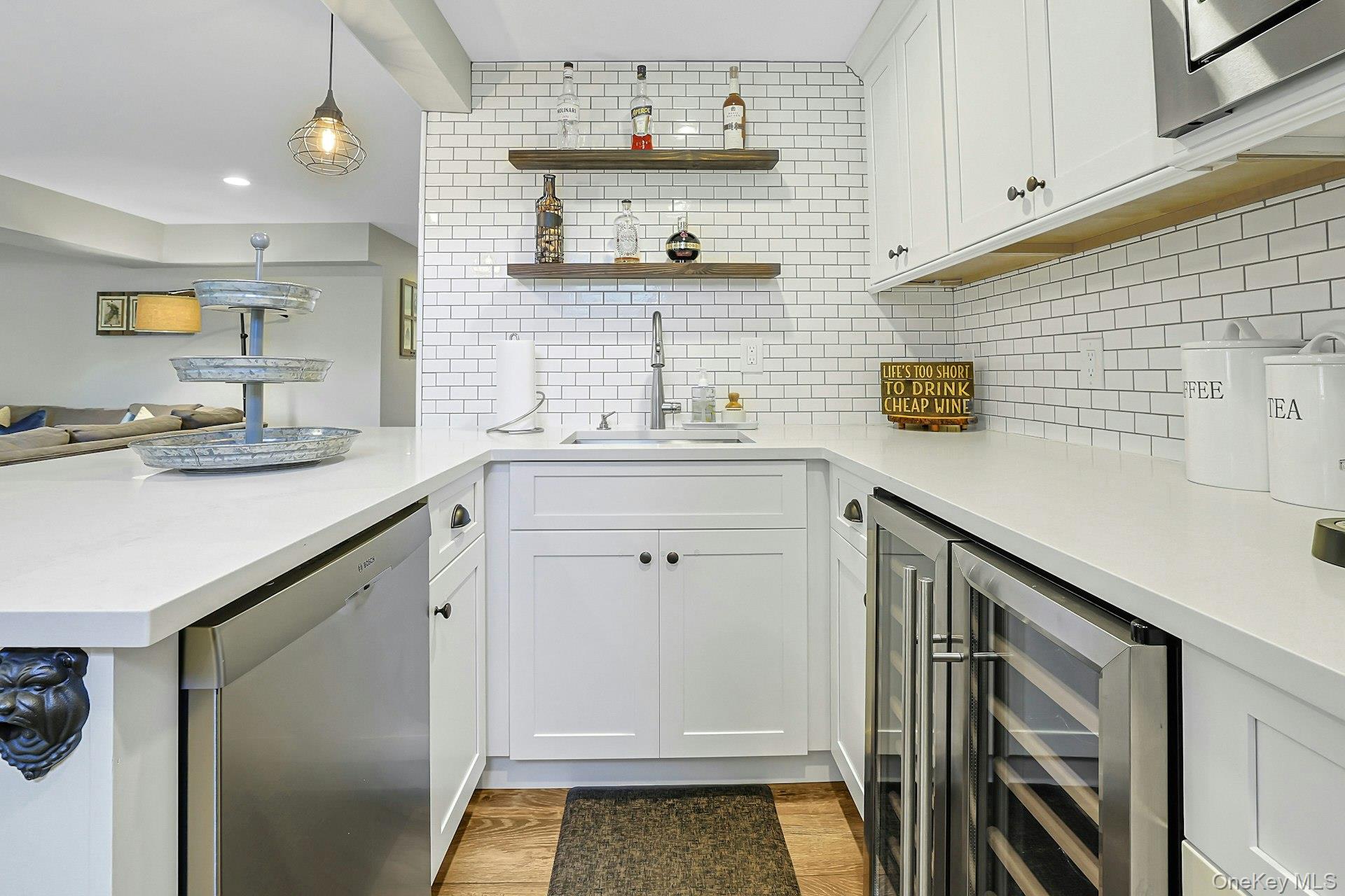 9 Stonegate Road Valhalla, NY 10595 - Photo 38 of 42 White subway tile backsplash, white cabinetry, integrated stainless steel dishwasher, built-in beverage refrigerator, and open wood shelving