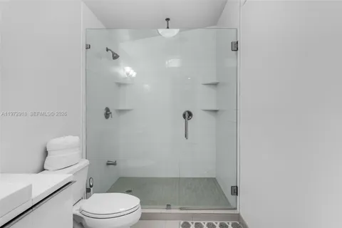 a bathroom with a granite countertop shower a toilet and a sink