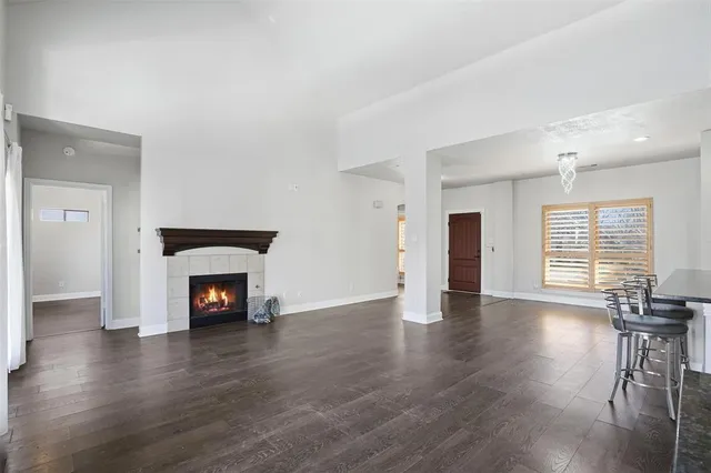 an empty room with wooden floor fireplace and windows
