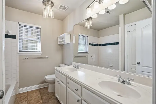 a bathroom with a double vanity sink a mirror and a toilet