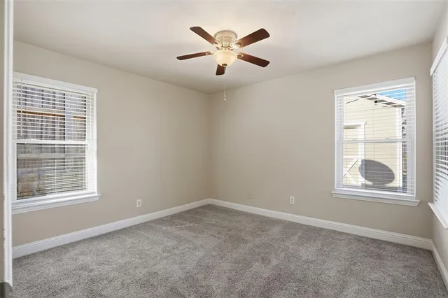 an empty room with windows and ceiling fan